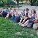 ca. 15 Sängerinnen sitzen auf einer Wiese und essen Falafel